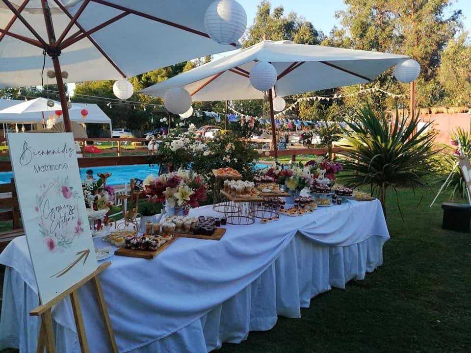Mesa dulce de matrimonio junto a la piscina de Kaas Eventos, con quitasoles y faroles de papel