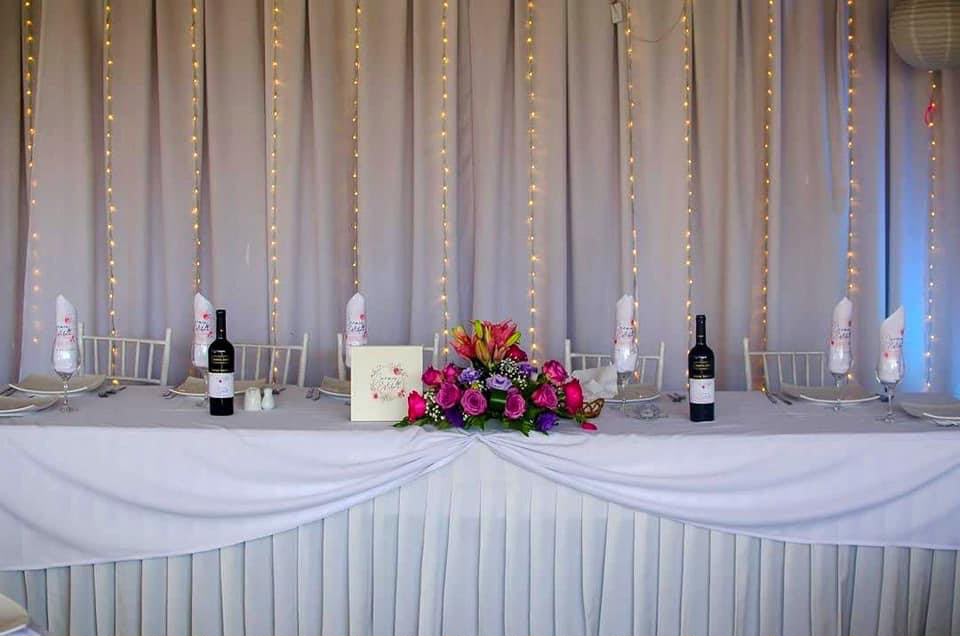 Mesa de los novios en Kaas Eventos con flores, cortina de luces y sillas blancas