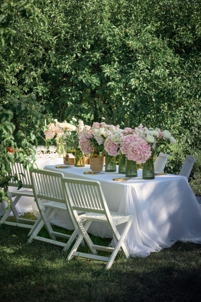 Mesa al aire libre con flores y sillas blancas